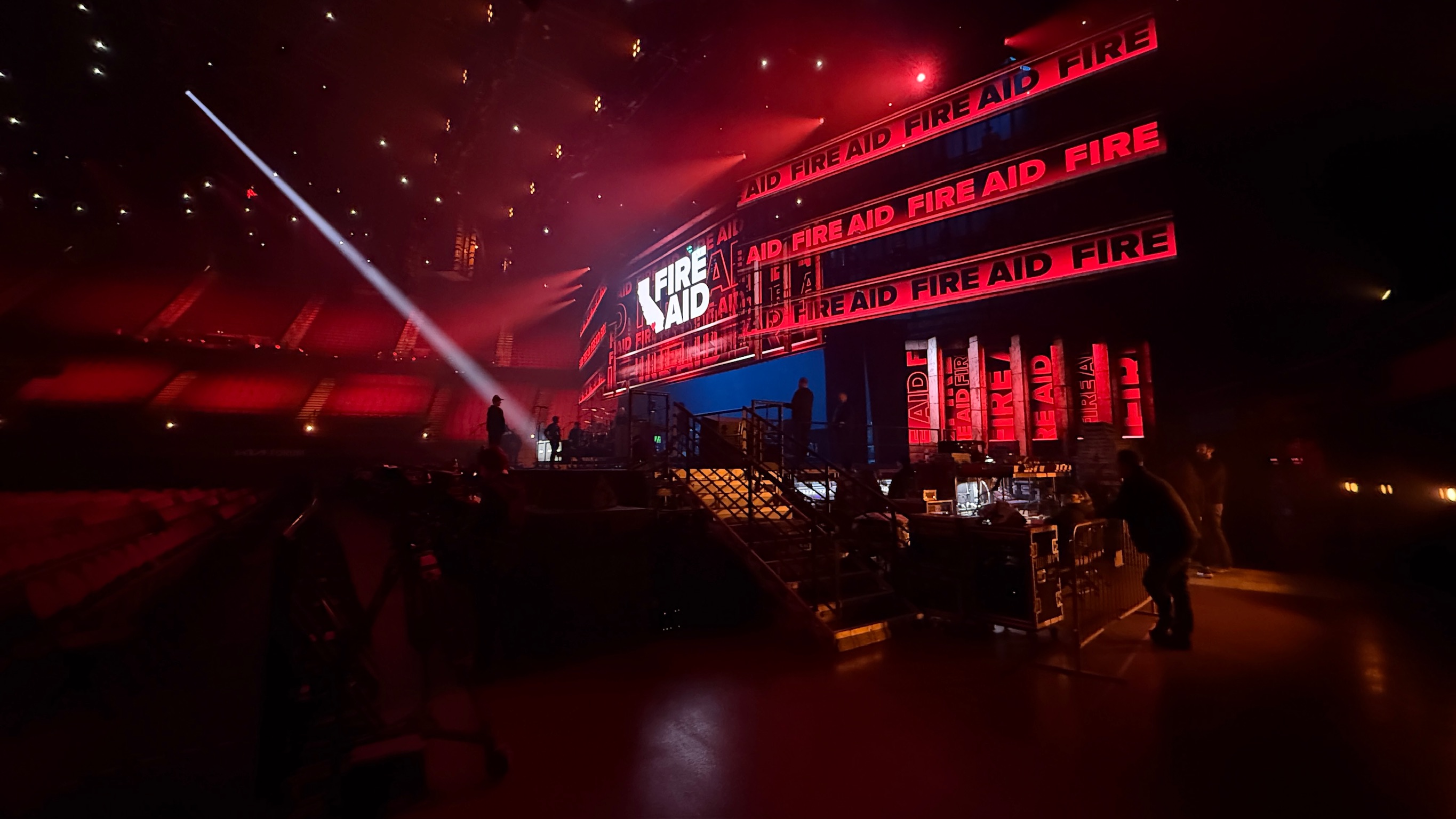 FireAid 2025 — Kia Forum stage in red light with FIRE AID branding on LED ribbons, pre-show